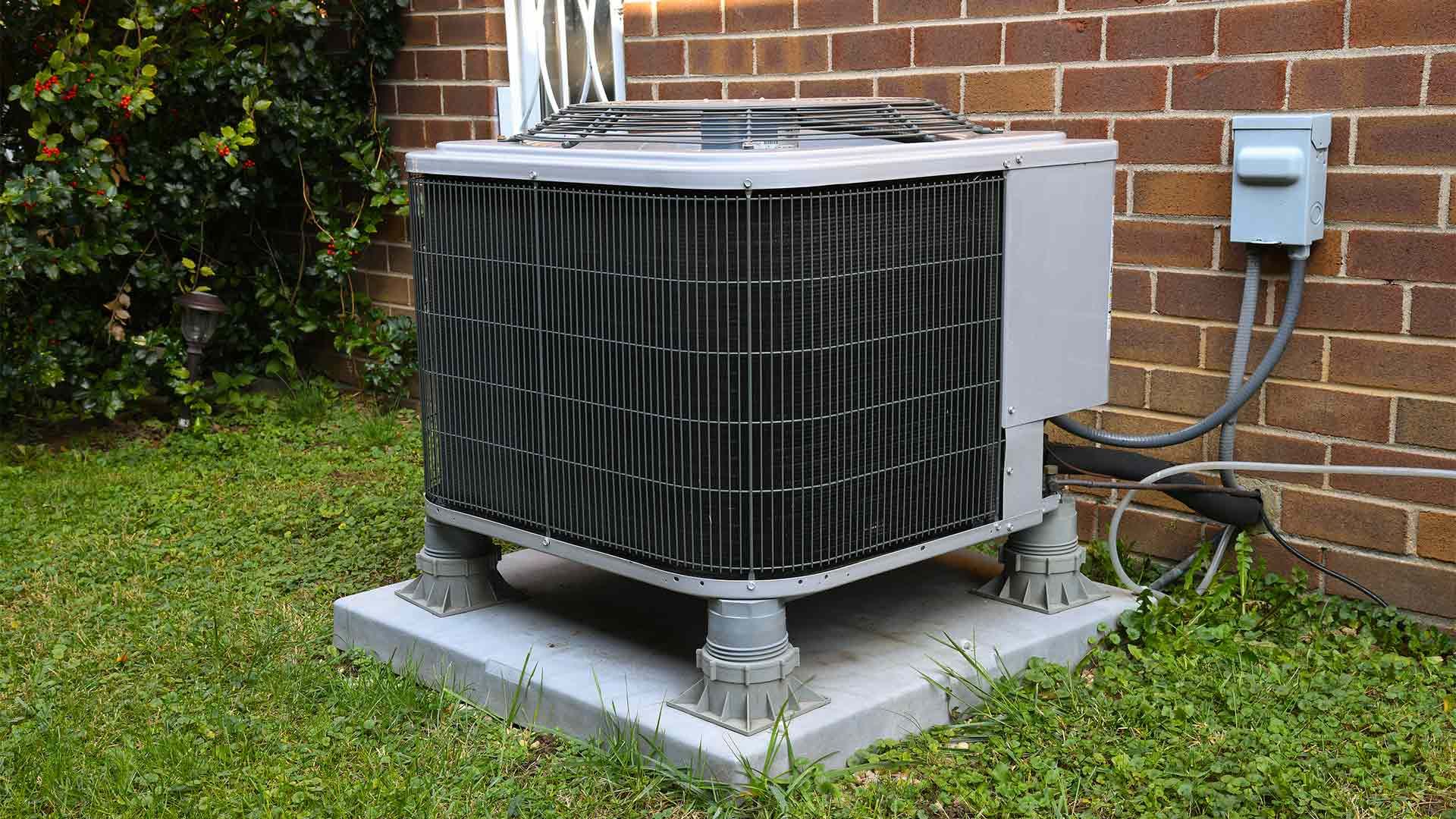 An air conditioner is sitting outside of a brick building.