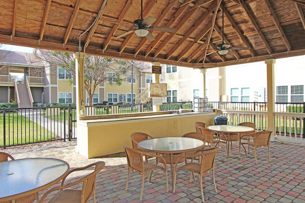 a gazebo with tables and chairs under a thatched roof