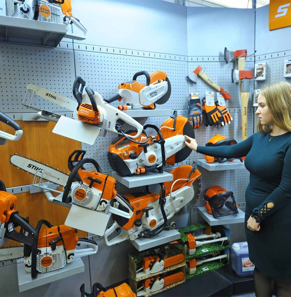 A woman is looking at a display of stihl chainsaws