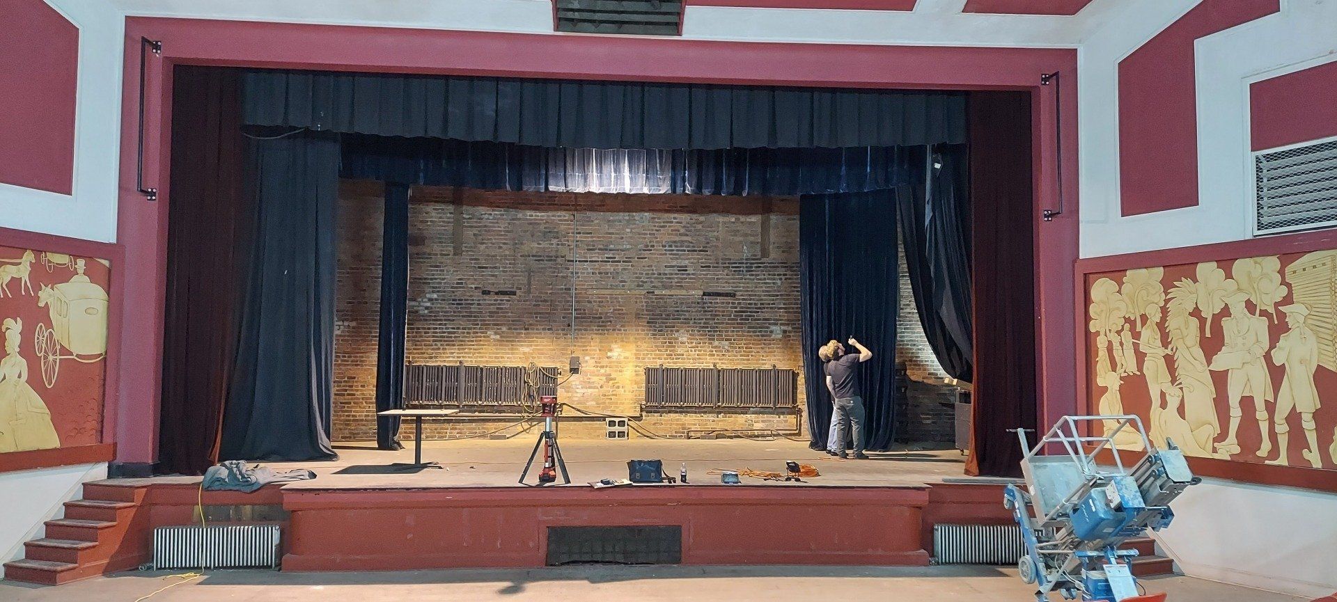 A man is standing in front of a stage in a theater.