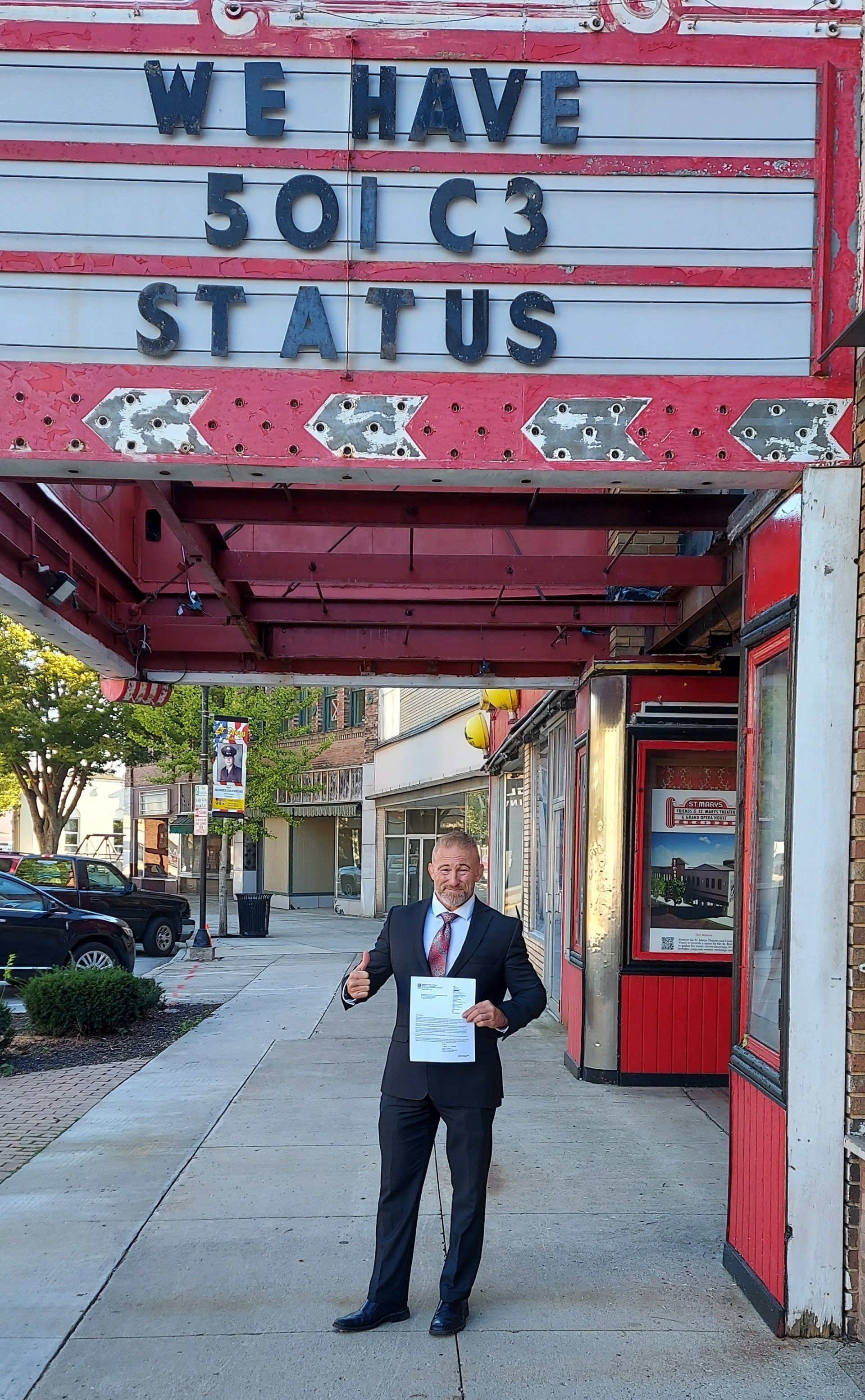 A man in a suit and tie is standing in front of a sign that says `` we have solc3 status ''.