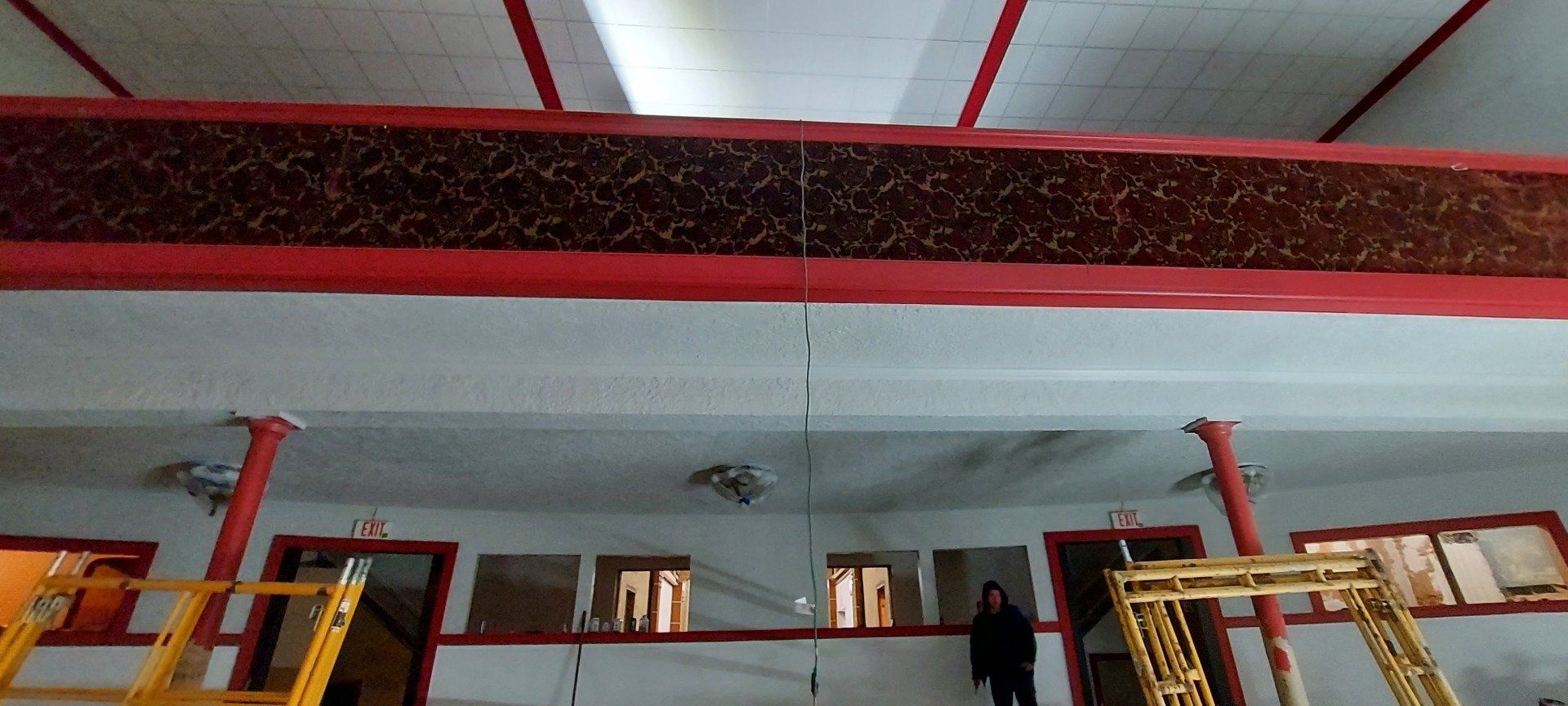 A man is standing on a ladder in a room with a red ceiling.