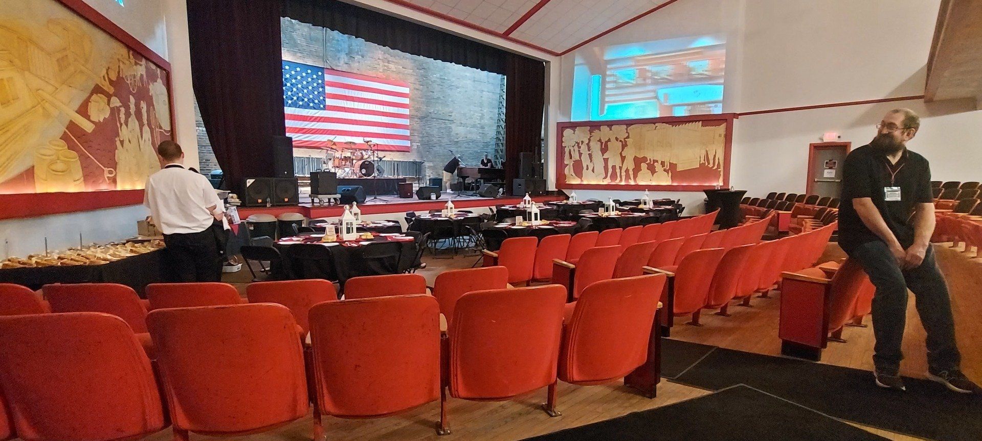 A man is standing in front of a stage in an auditorium.