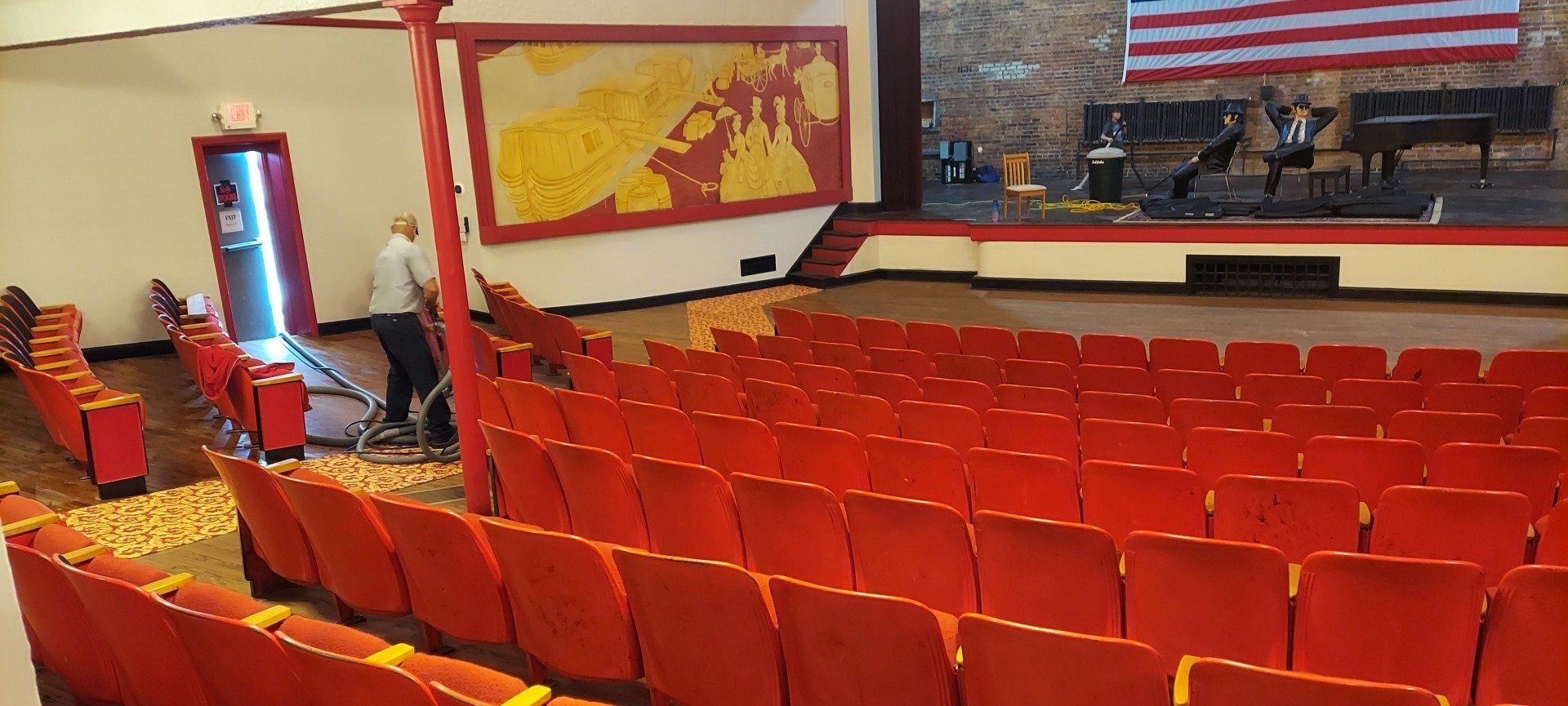 An empty auditorium with red seats and an american flag on the wall.