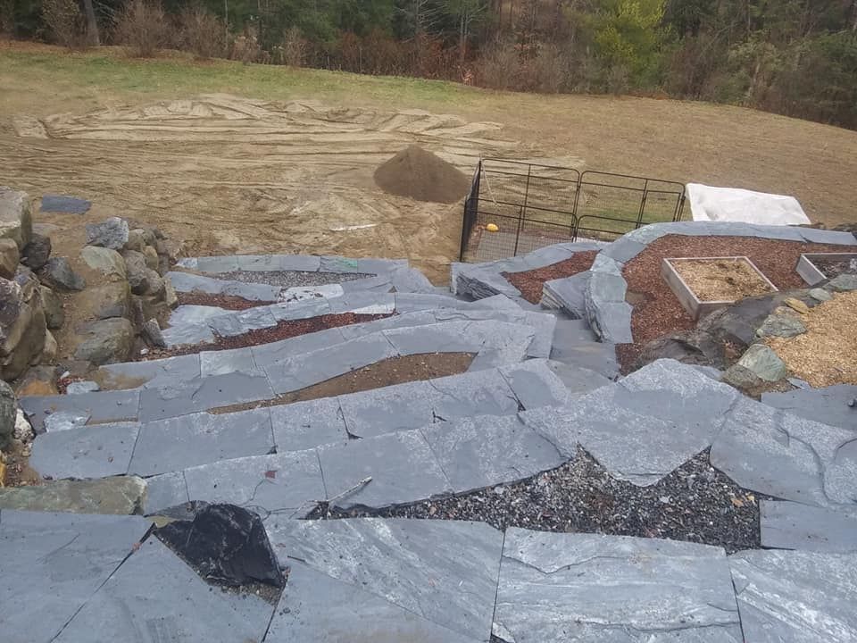 Stone steps leading down a sloped yard, surrounded by rocks and landscaping.