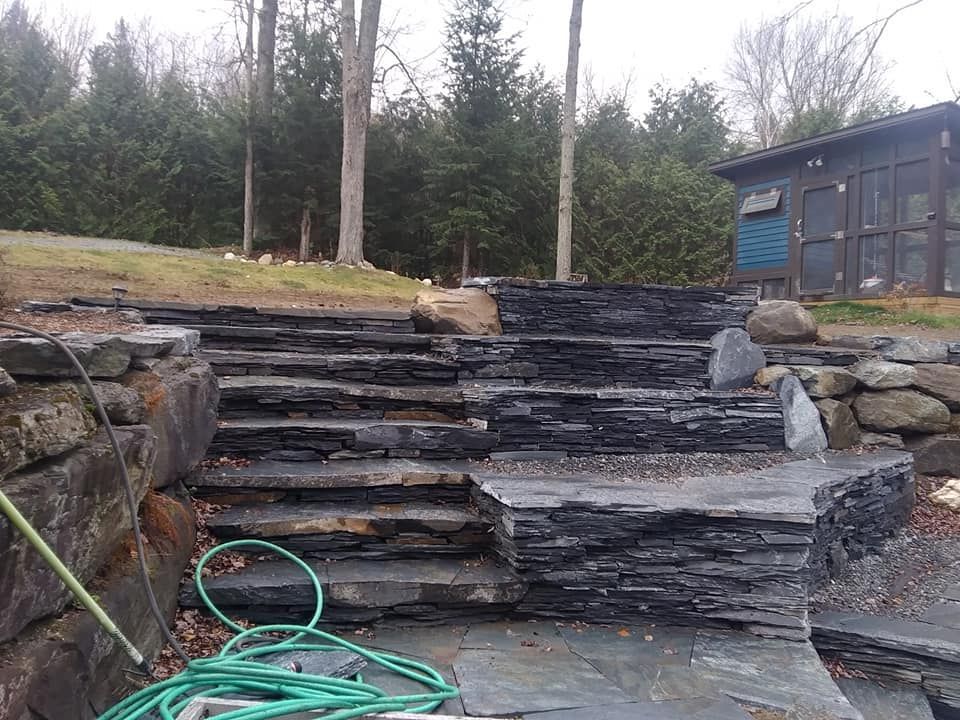 Stone steps leading up a sloped landscape with trees in the background. A shed is to the right.