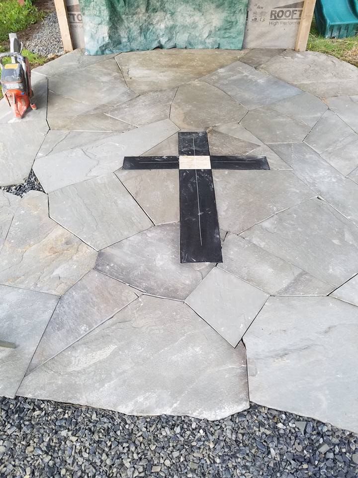 Stone patio with a black and white cross inlay.