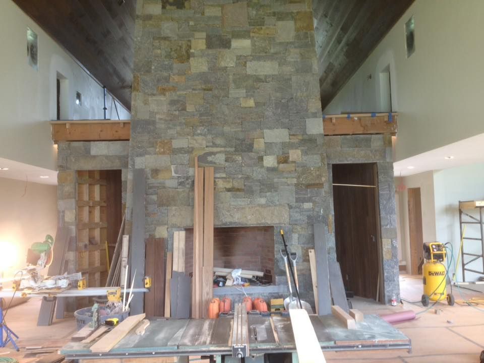 Stone fireplace under construction with tools and lumber scattered around.