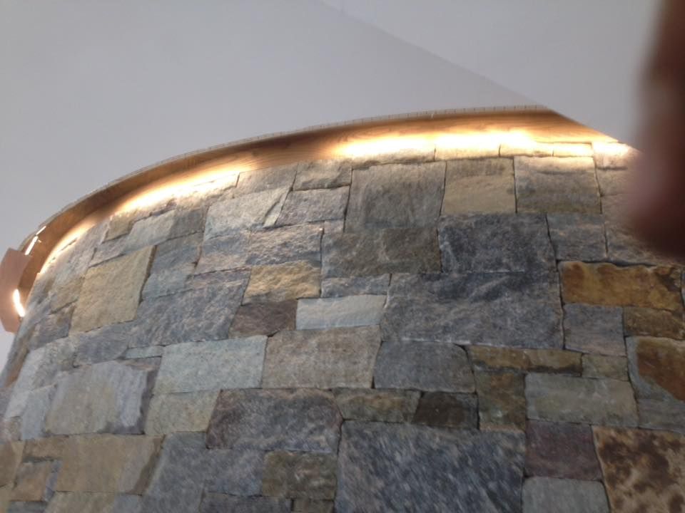 Stone pillar with indirect lighting against white ceiling.