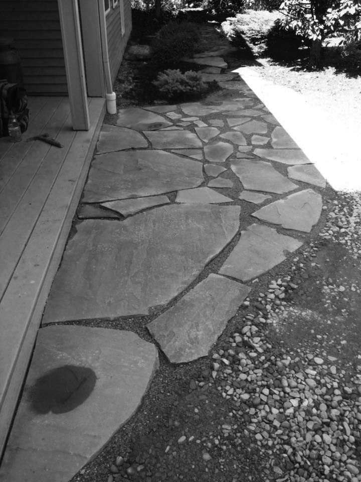 Flagstone path alongside a house, with small rocks bordering the stones.