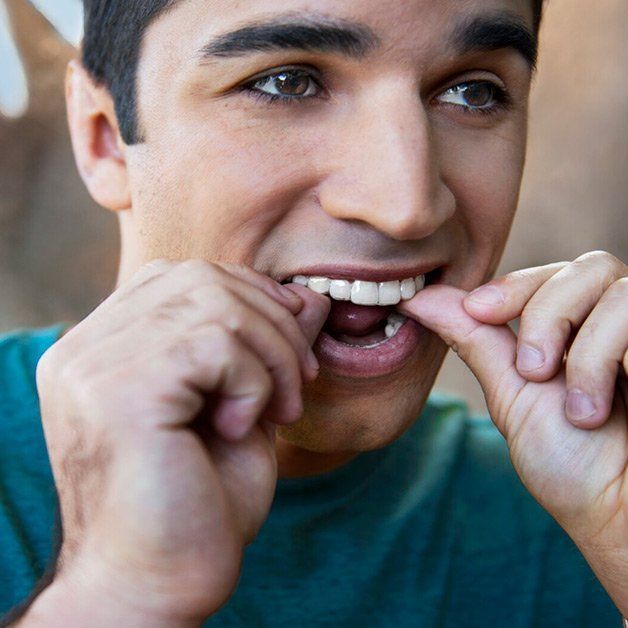 A man is brushing his teeth with a clear brace.