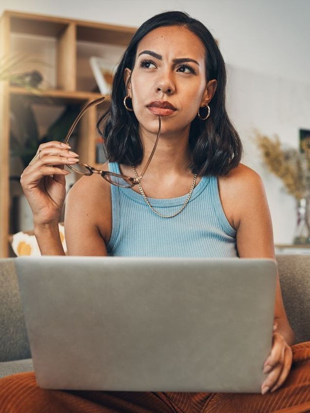 Una mujer está sentada en un sofá usando una computadora portátil.