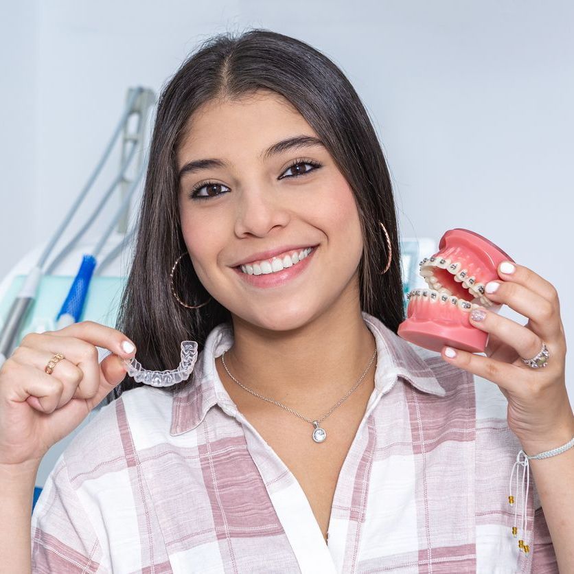 A woman is smiling while holding a model of her teeth.