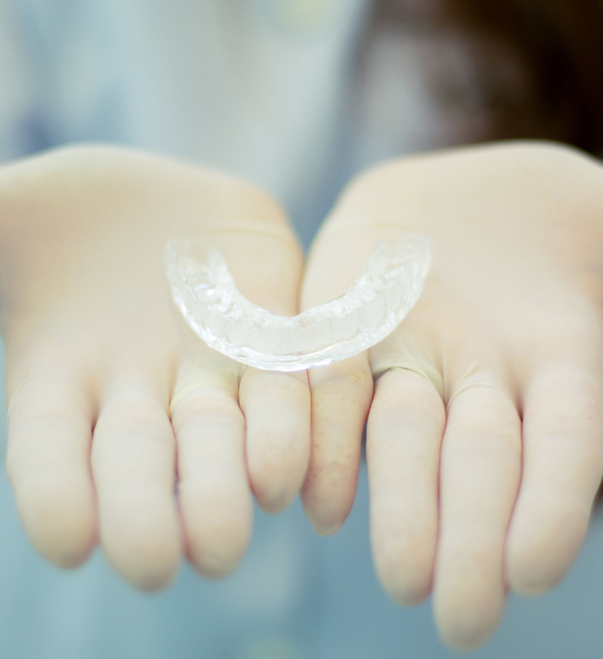 A person is holding a clear mouth guard in their hands.