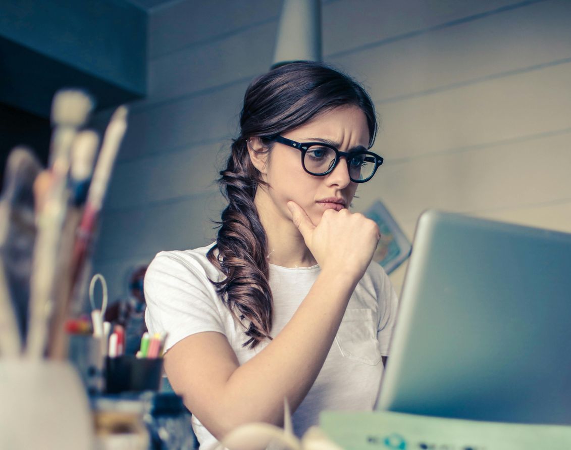 Una mujer con gafas está mirando una computadora portátil.