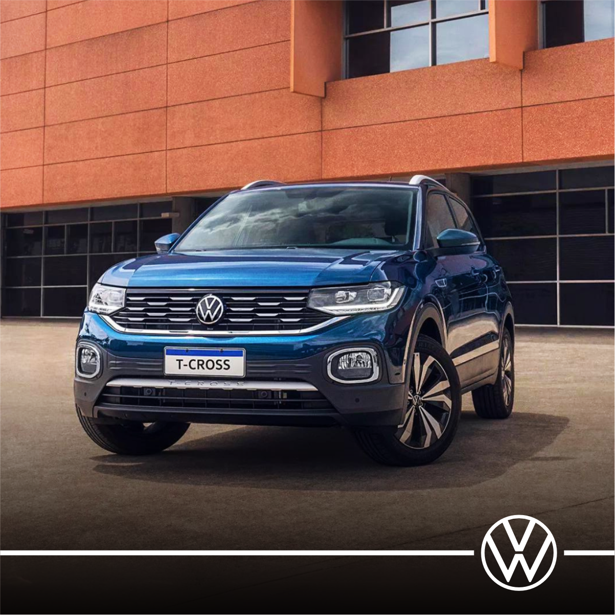 Um volkswagen t cross azul está estacionado em frente a um prédio.