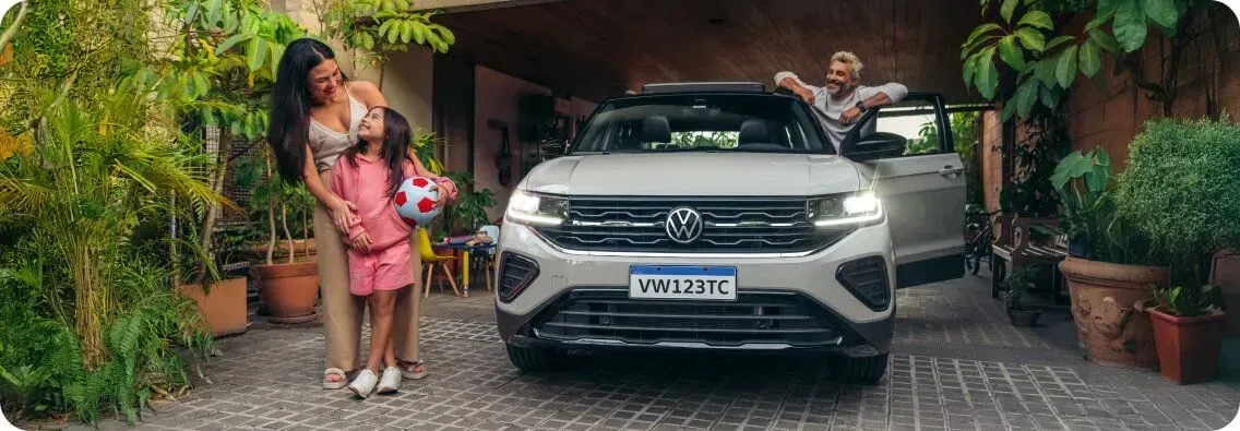 Uma família está perto de um SUV cinza. Uma mulher e uma criança estão à esquerda
