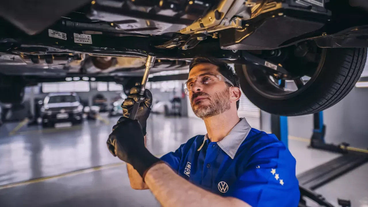 Um homem está trabalhando em um carro em uma garagem.