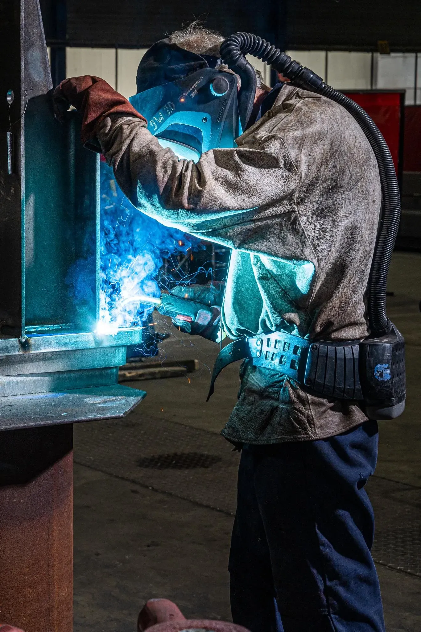 Een man met een lasmasker is een stuk metaal aan het lassen. Door Willems Boven-Leeuwen.