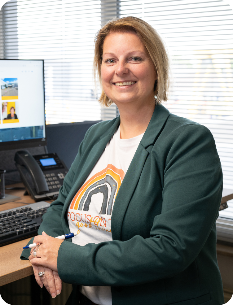 Een vrouw in een shirt met luipaardprint glimlacht voor een gele muur. Ramona Meijer