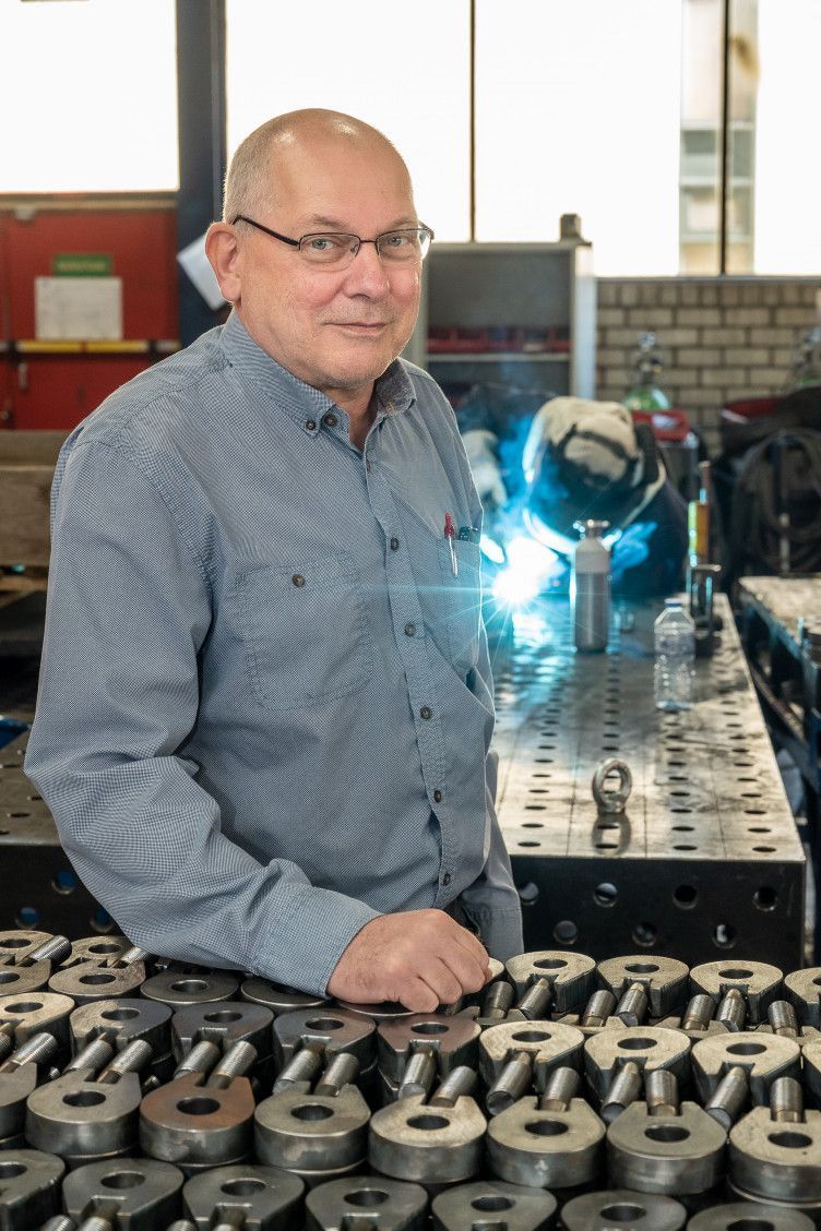 Een man leunt op een tafel in een fabriek. Wim van Dinther.