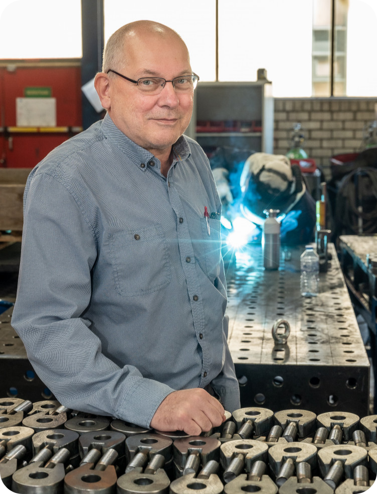 Een man leunt op een tafel in een fabriek. Wim van Dinther.