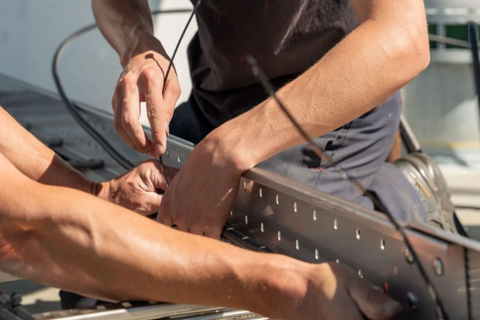 Een stapel van meerdere parallelle, geperforeerde metalen stroken die onder een hoek zijn uitgelijnd tegen een donkere achtergrond.