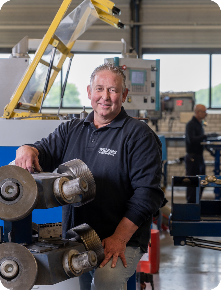 Een man staat voor een machine in een fabriek. Geert Tijnagel.