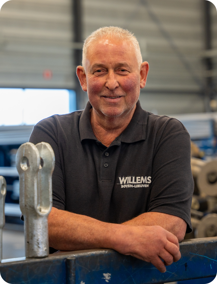 Een man staat voor een machine in een fabriek. Geert Tijnagel.