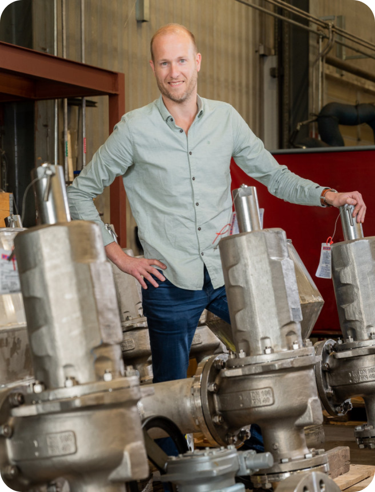 Een man staat voor een rij kleppen in een fabriek. Dirk Boekhorst.