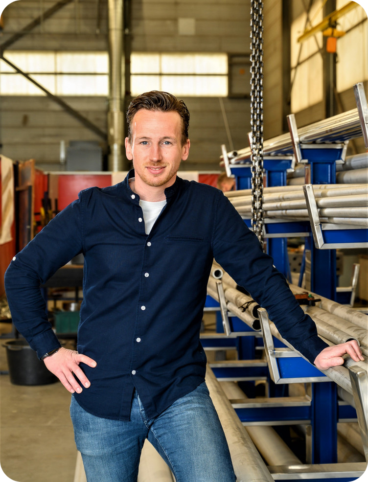 Een man staat in een pakhuis met zijn handen op zijn heupen. Hidde van Kessel