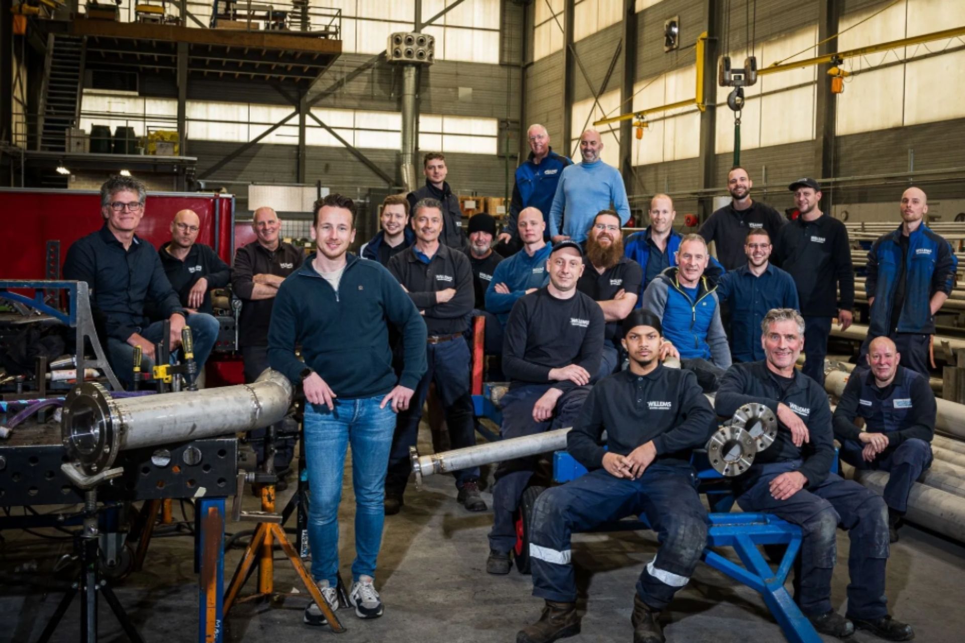 Een stapel gebogen, metalen industriële panelen in een helder verlichte, ruime werkplaats of productiehal.