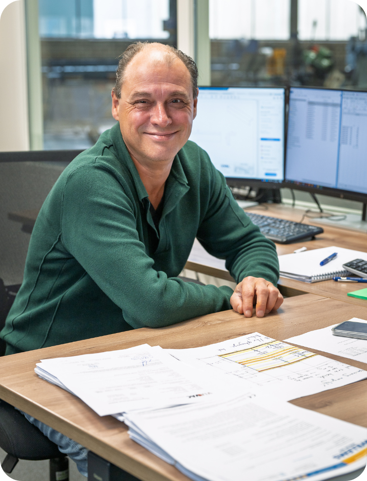 Een man leunt op een tafel in een fabriek. Wim van Dinther.