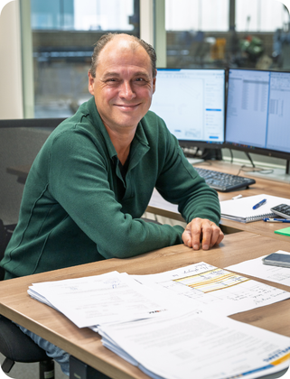 Een man leunt op een tafel in een fabriek. Wim van Dinther.