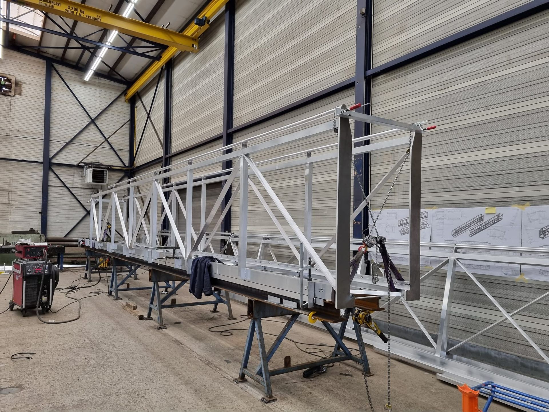 Een man in een oranje jasje staat 's nachts voor een groot gebouw.