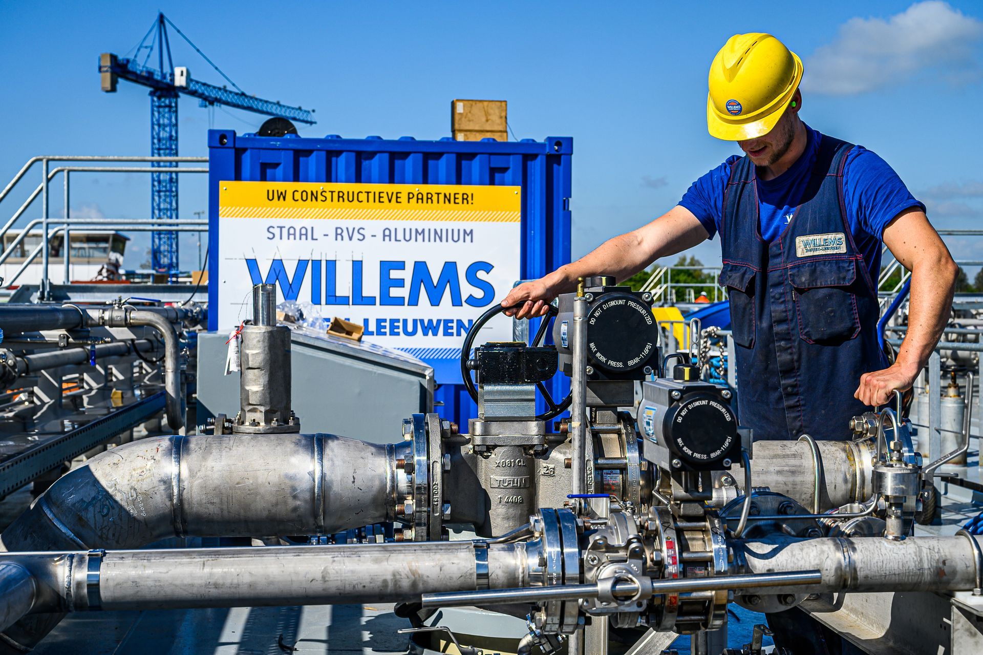Een man werkt aan een machine voor een bord met de tekst willems.