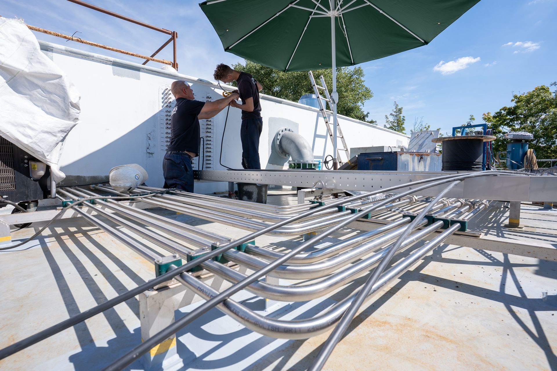 Een groot, metalen, veelzijdig cirkelvormig afdek- of dakelement dat op een grindterrein staat onder een bewolkte hemel.