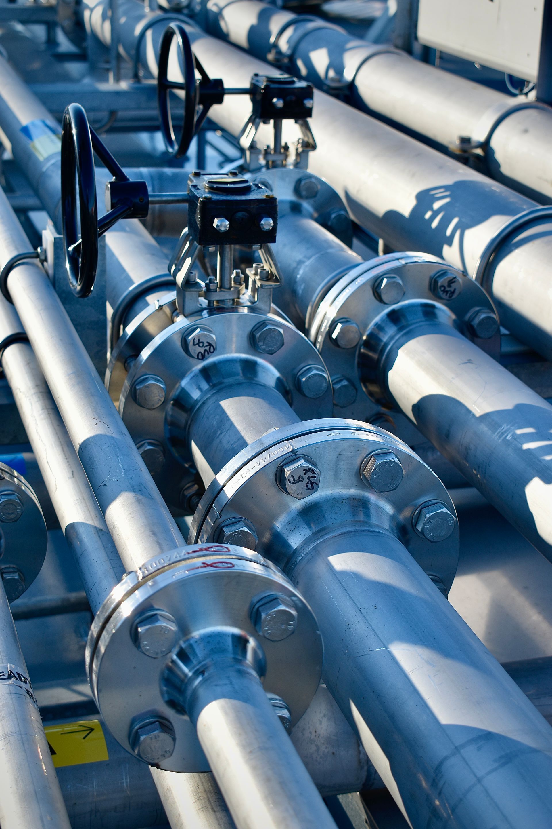 Een stel pijpen met kleppen erop in een fabriek. Door Willems Boven-Leeuwen.
