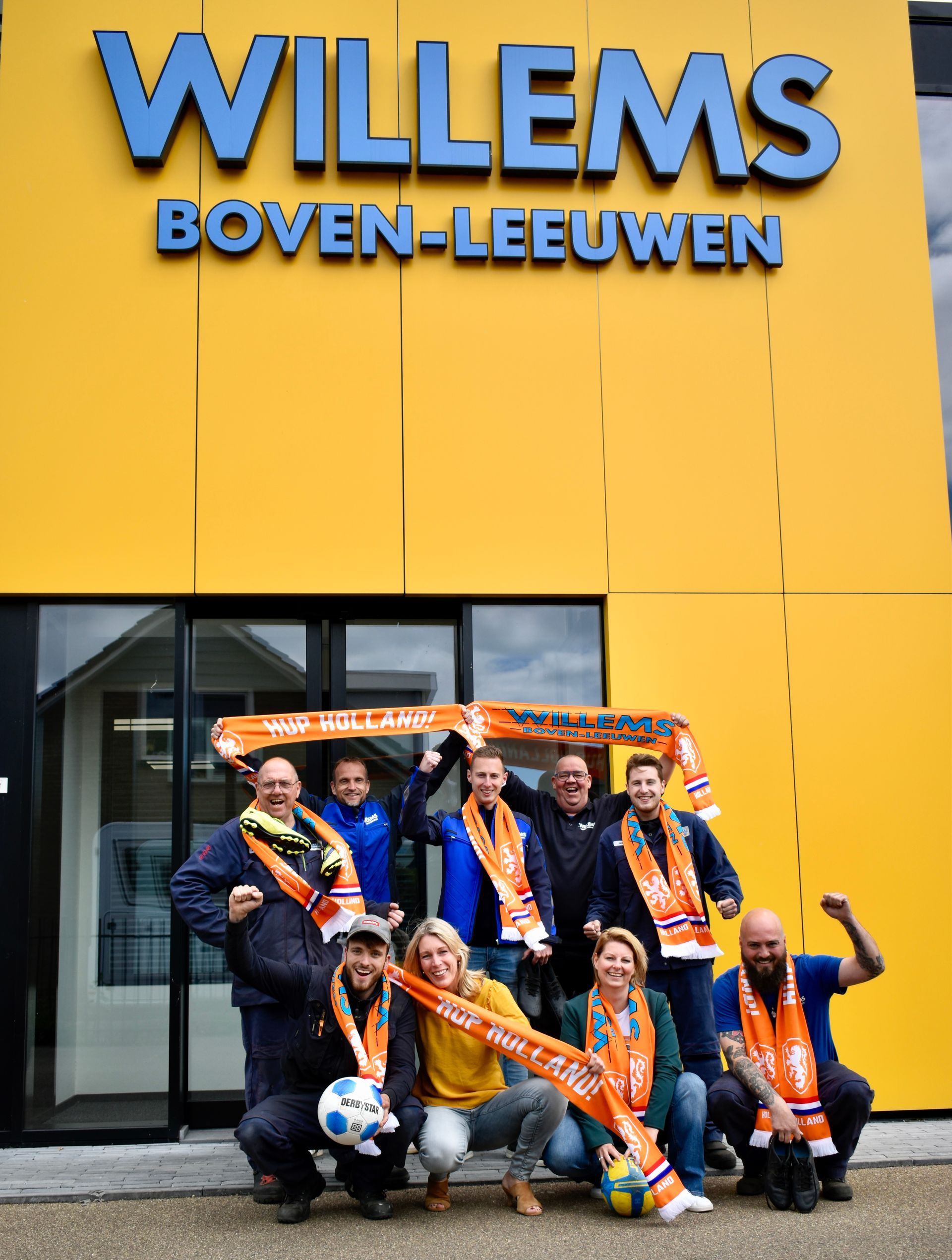 Een groep juichende mensen van Willems Boven-Leeuwen in Oranje kleding die het EK supporten