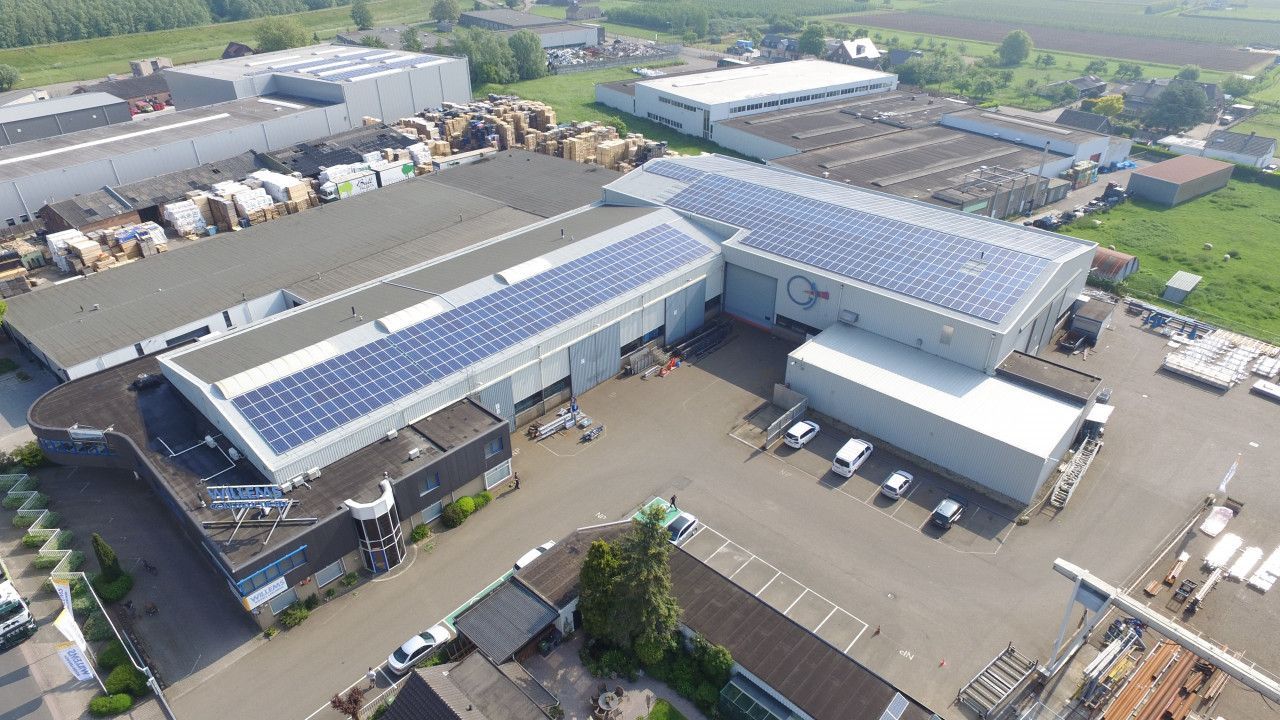 Een luchtfoto van een fabriek met zonnepanelen op het dak.