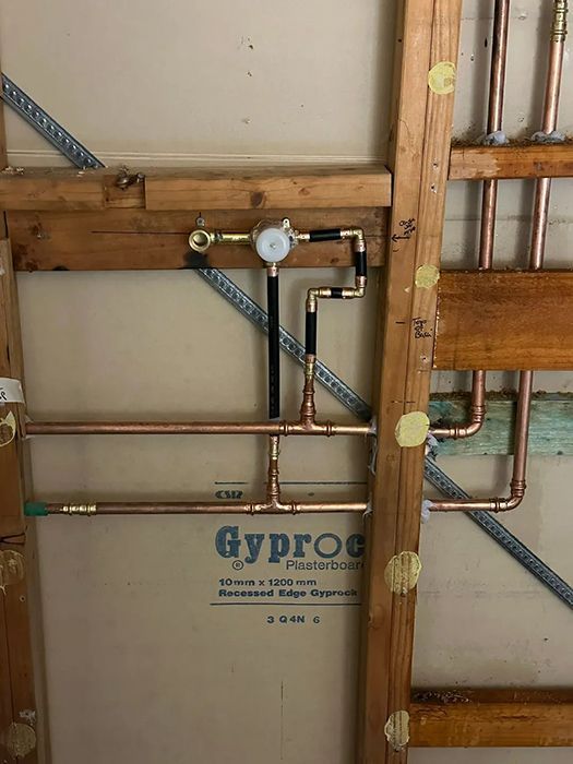 A Bathroom With Copper Pipes Hanging From The Ceiling — Gordo's Plumbing Service In Wagga Wagga, NSW