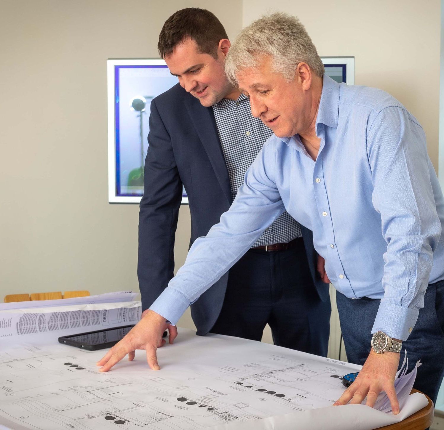 two men are looking at a blueprint of a building
