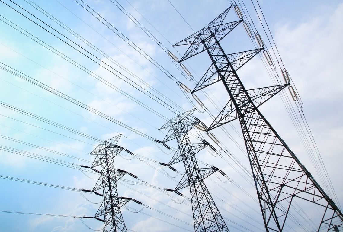 Looking upwards at three pylons against a blue, cloudy sky.