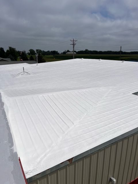 A close-up of a house exterior featuring a gable-roof dormer with dark gray siding and white trim against a blue sky.