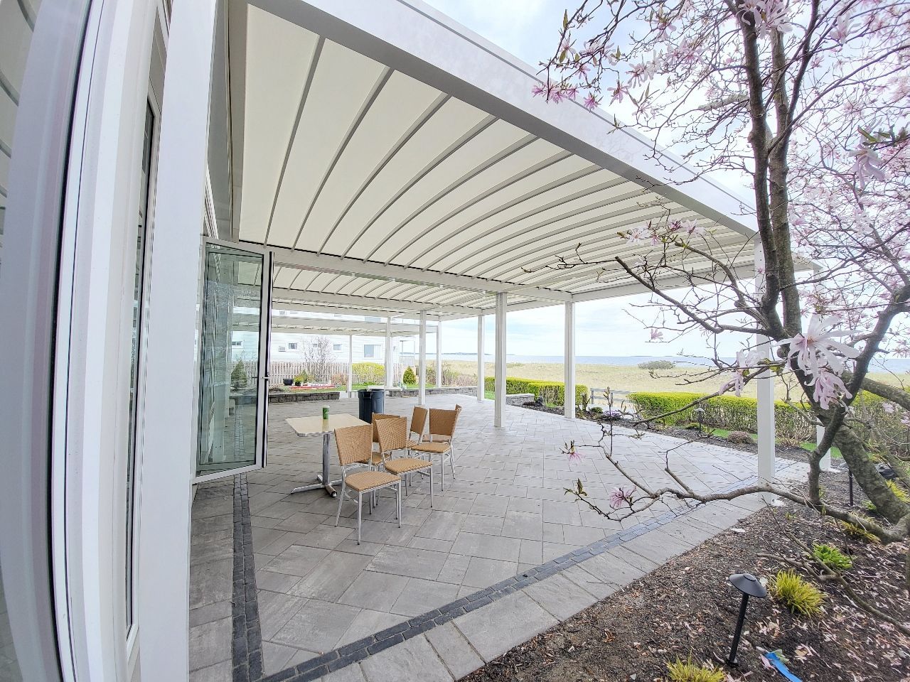 There is a patio with a table and chairs under a canopy - Freehold, NJ - Awning Design Inc