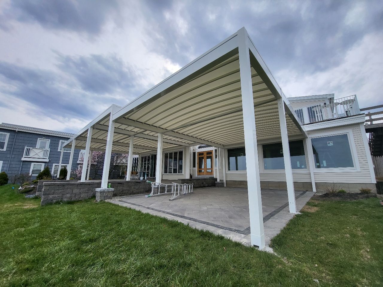 A large white pergola is sitting in the backyard of a house - Freehold, NJ - Awning Design Inc