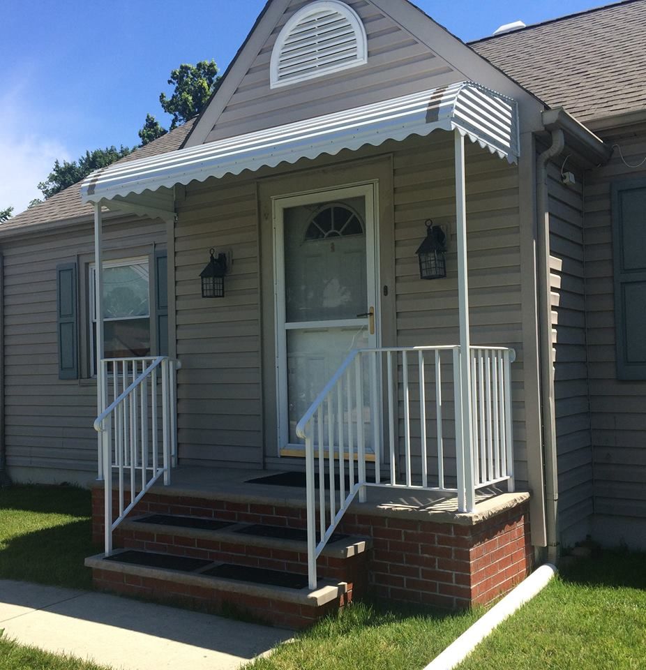 A house with a white awning over the front door - Freehold, NJ - Awning Design Inc
