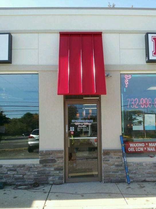 A store front with a red awning over the door