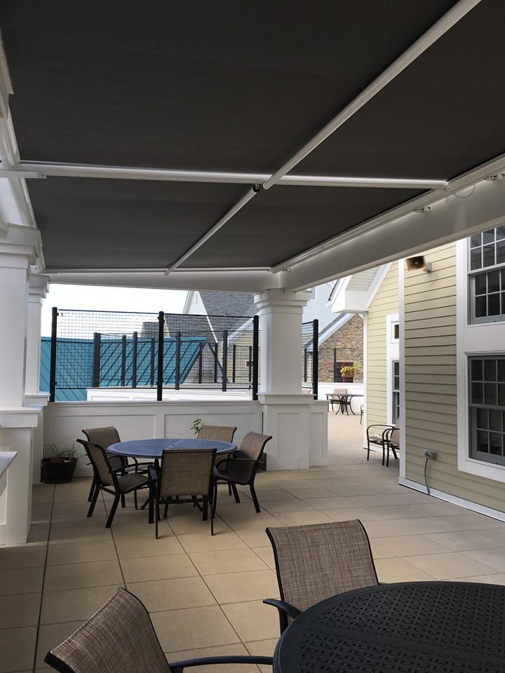 A patio with a table and chairs under an awning - Freehold, NJ - Awning Design Inc