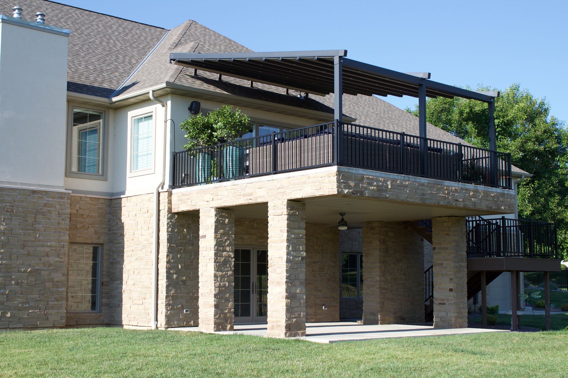 A large brick house with a balcony and a pergola - Freehold, NJ - Awning Design Inc